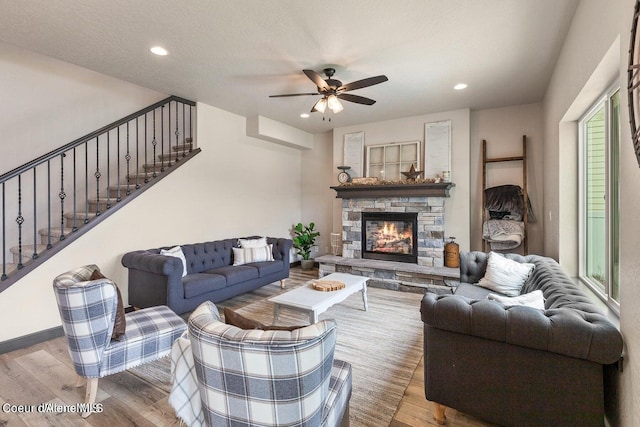 living room with a stone fireplace, hardwood / wood-style flooring, ceiling fan, a textured ceiling, and a wealth of natural light