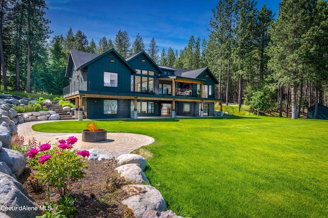 rear view of property featuring a lawn, a deck, and an outdoor fire pit