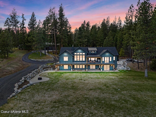 back house at dusk featuring a yard