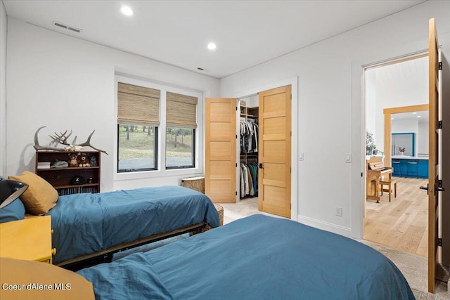 bedroom featuring a walk in closet, a closet, and light hardwood / wood-style floors