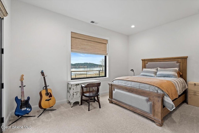 bedroom featuring a water view and light carpet