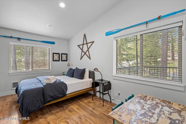 bedroom featuring hardwood / wood-style floors, lofted ceiling, and multiple windows