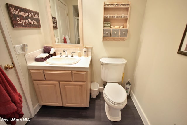 bathroom featuring toilet, baseboards, wood finished floors, and vanity