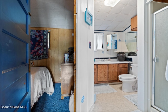 bathroom with vanity, toilet, walk in shower, and wood walls