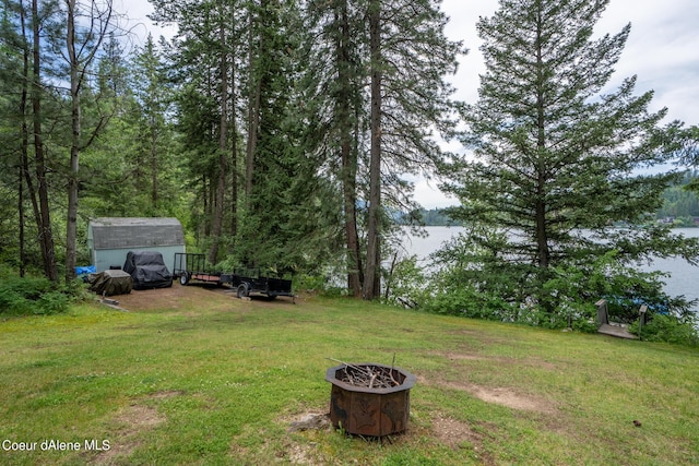 view of yard with a fire pit, a storage shed, and a water view