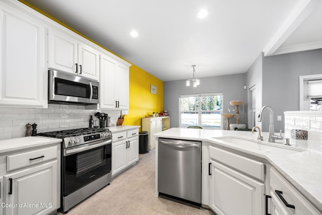 kitchen featuring sink, appliances with stainless steel finishes, backsplash, hanging light fixtures, and white cabinets