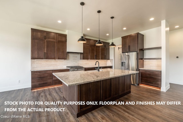 kitchen featuring appliances with stainless steel finishes, light stone counters, dark brown cabinetry, a kitchen island with sink, and dark wood-type flooring