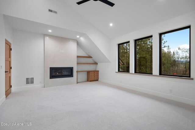 unfurnished living room featuring a fireplace, light colored carpet, vaulted ceiling, and ceiling fan