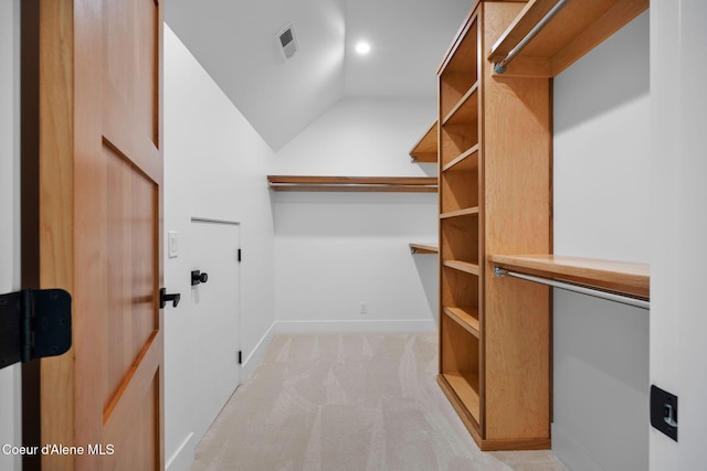 spacious closet with light colored carpet and vaulted ceiling