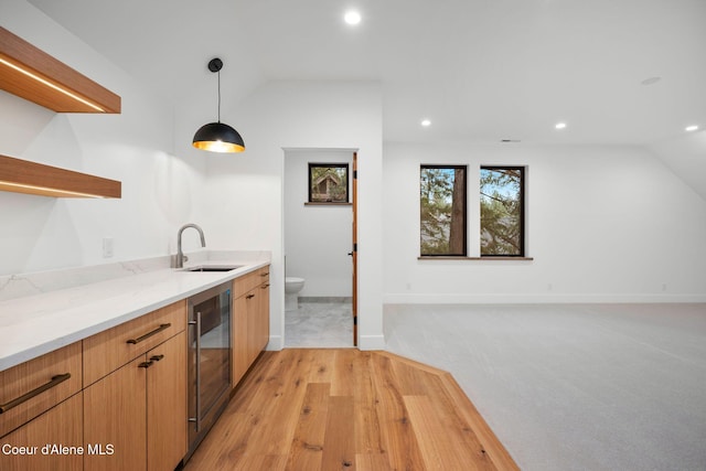 kitchen featuring light stone countertops, sink, wine cooler, lofted ceiling, and decorative light fixtures