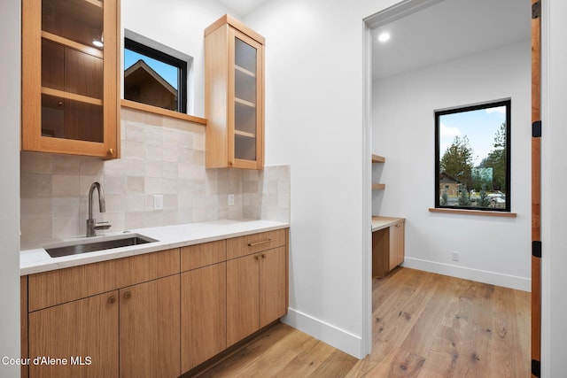 kitchen with tasteful backsplash, sink, and light hardwood / wood-style floors