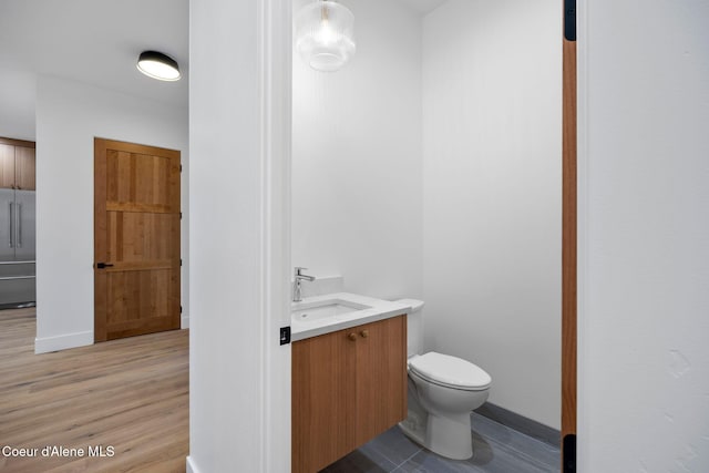 bathroom with hardwood / wood-style floors, vanity, and toilet