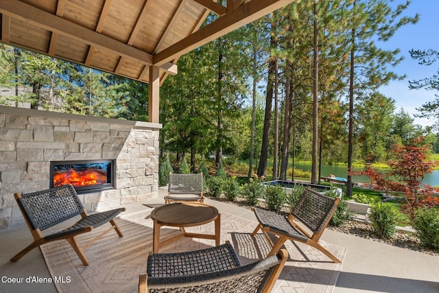 view of patio / terrace featuring an outdoor stone fireplace and a water view