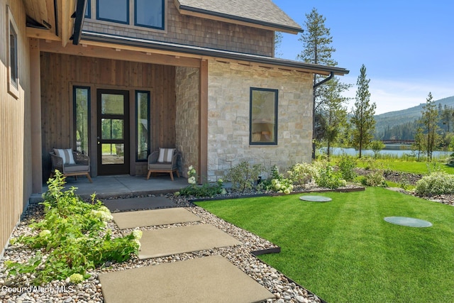 doorway to property with a lawn and a water view