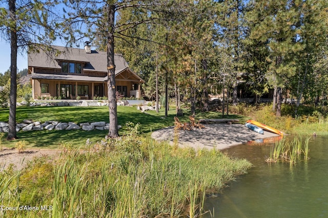 back of house featuring a yard and a water view