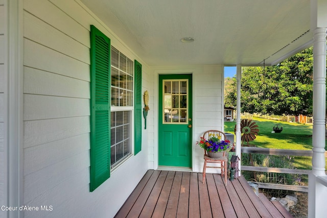 view of exterior entry featuring a porch and a lawn