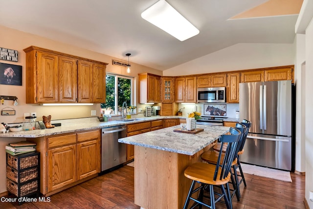 kitchen with sink, a center island, stainless steel appliances, light stone counters, and lofted ceiling