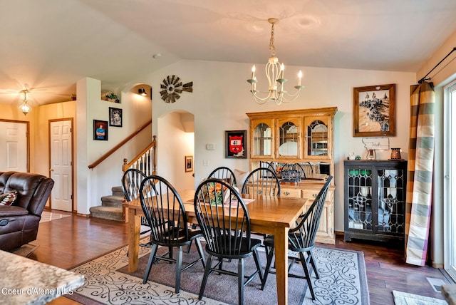 dining area with dark hardwood / wood-style flooring, lofted ceiling, and an inviting chandelier