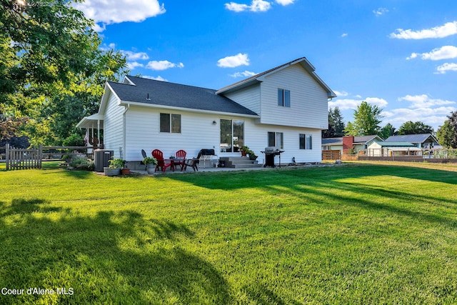 rear view of property featuring a yard, central AC, and a patio area