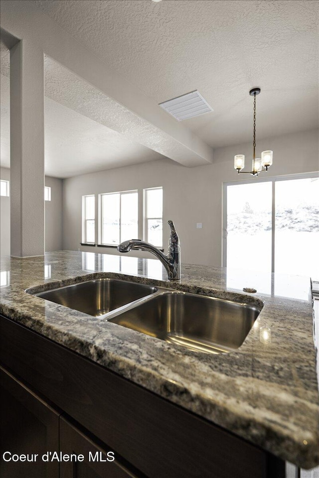 kitchen featuring a textured ceiling, a notable chandelier, a healthy amount of sunlight, and sink