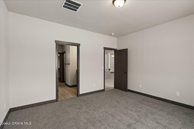 unfurnished bedroom with a textured ceiling and dark colored carpet