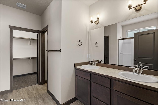 bathroom featuring wood-type flooring, vanity, a textured ceiling, and an enclosed shower