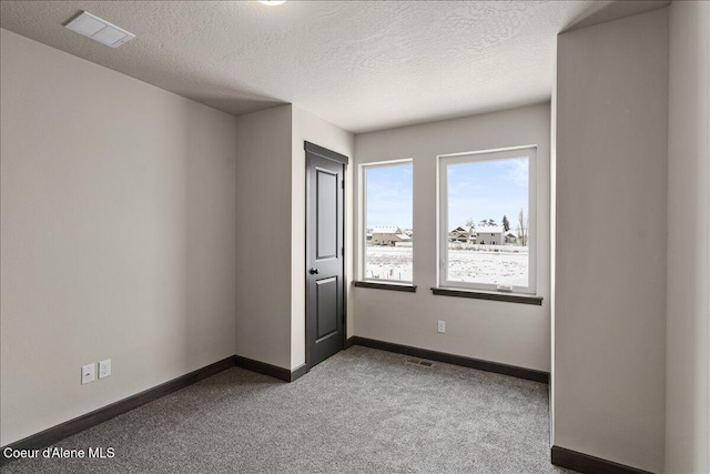 carpeted empty room featuring a textured ceiling