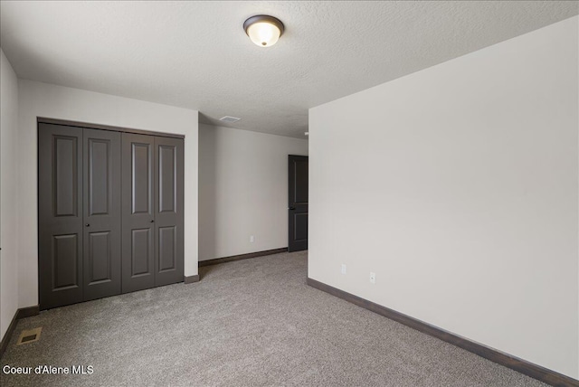 unfurnished bedroom with light carpet, a textured ceiling, and a closet