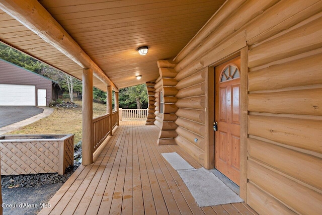 deck featuring covered porch, an outdoor structure, and a garage