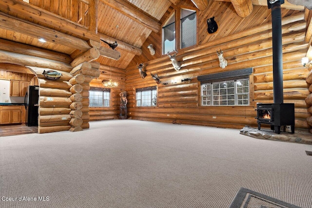 unfurnished living room with rustic walls, beam ceiling, high vaulted ceiling, wooden ceiling, and a wood stove