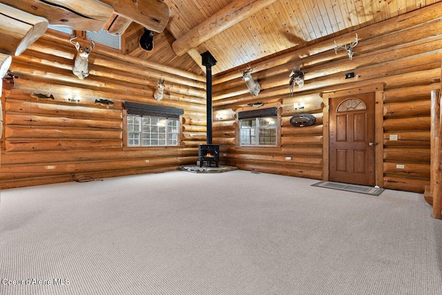 unfurnished living room with beam ceiling, a wood stove, rustic walls, carpet floors, and wood ceiling