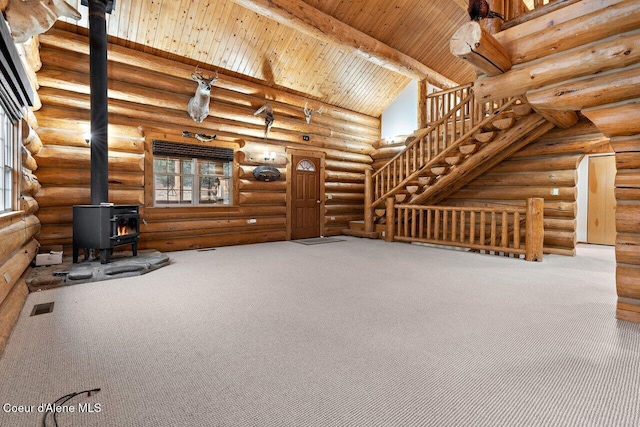 unfurnished living room featuring lofted ceiling with beams, a wood stove, rustic walls, and wooden ceiling