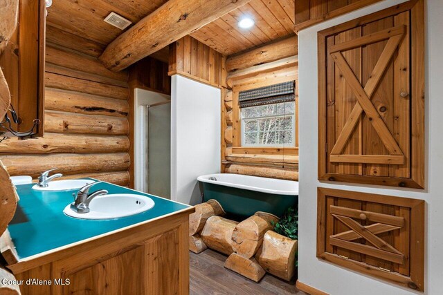 bathroom featuring a washtub, beam ceiling, wood-type flooring, and rustic walls