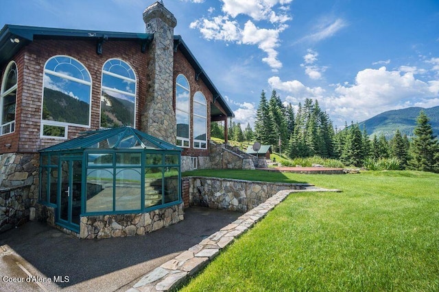 back of property featuring a mountain view, a yard, and an outbuilding