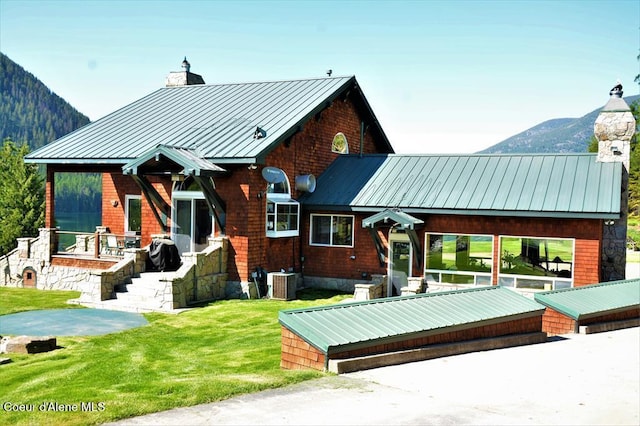 back of house with a lawn, a mountain view, and cooling unit