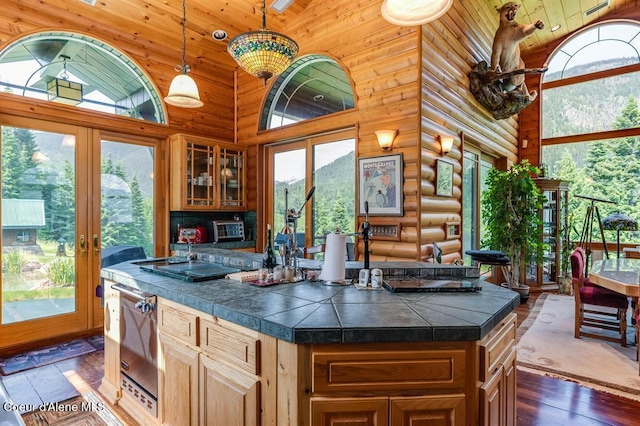 kitchen with french doors, rustic walls, high vaulted ceiling, a kitchen island, and hanging light fixtures