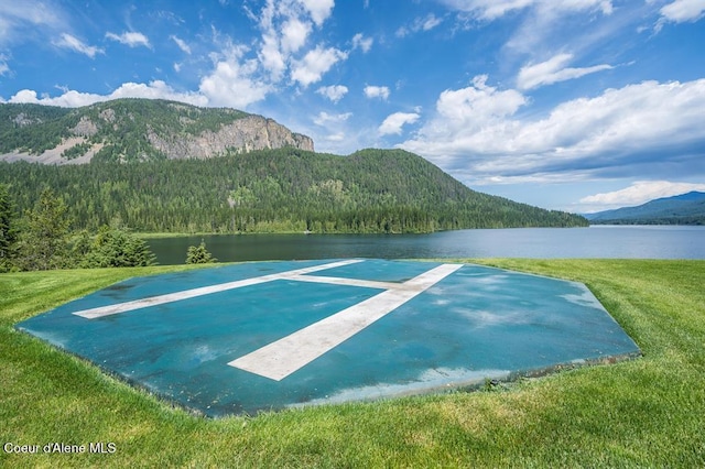 view of property's community featuring a water and mountain view and a lawn