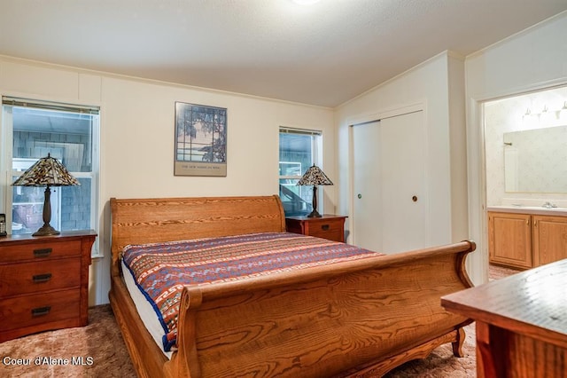 carpeted bedroom with ensuite bathroom, vaulted ceiling, a closet, and ornamental molding