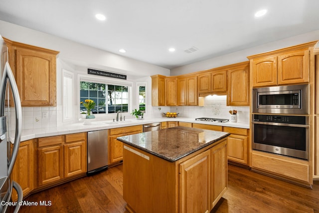 kitchen with appliances with stainless steel finishes, a center island, dark wood-type flooring, and backsplash