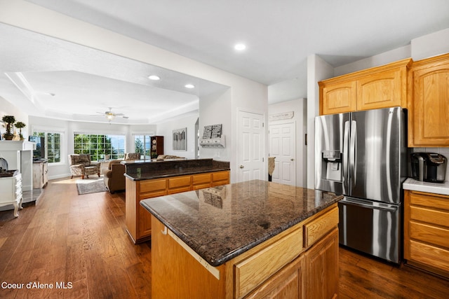 kitchen with ceiling fan, a kitchen island, dark wood-type flooring, and stainless steel refrigerator with ice dispenser