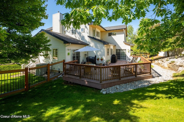 rear view of property featuring a lawn and a wooden deck