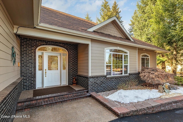 property entrance with brick siding and a shingled roof