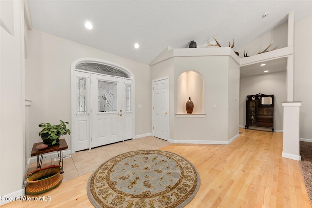 foyer entrance with light wood-style floors, lofted ceiling, baseboards, and recessed lighting