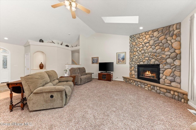 living area with baseboards, lofted ceiling with skylight, ceiling fan, carpet floors, and a fireplace