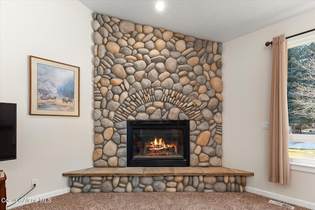 interior details with baseboards, a fireplace, visible vents, and carpet flooring