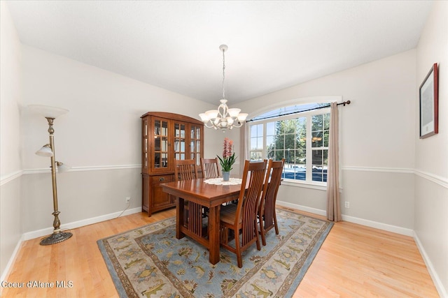 dining room featuring light wood-style floors, baseboards, and a notable chandelier