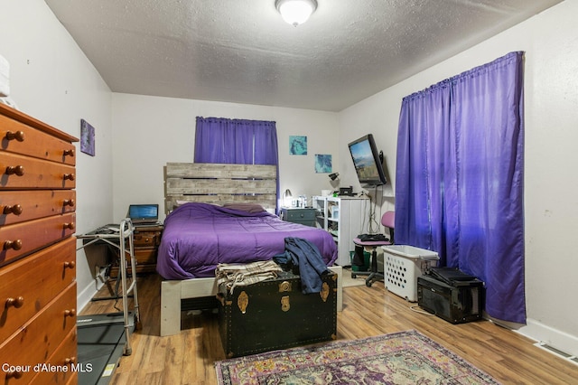 bedroom with a textured ceiling and hardwood / wood-style flooring