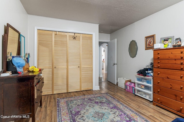 bedroom with a closet, a textured ceiling, and hardwood / wood-style flooring