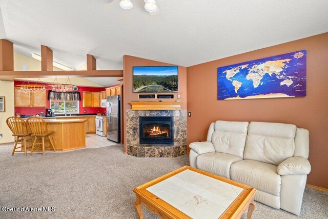 living room with indoor wet bar, light colored carpet, a premium fireplace, and vaulted ceiling