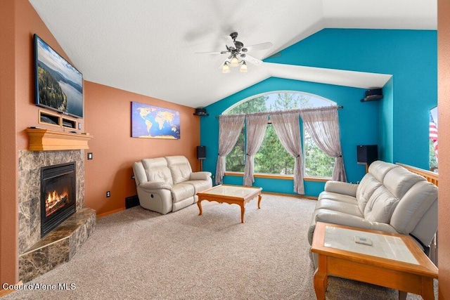 carpeted living room with ceiling fan, a tile fireplace, and vaulted ceiling